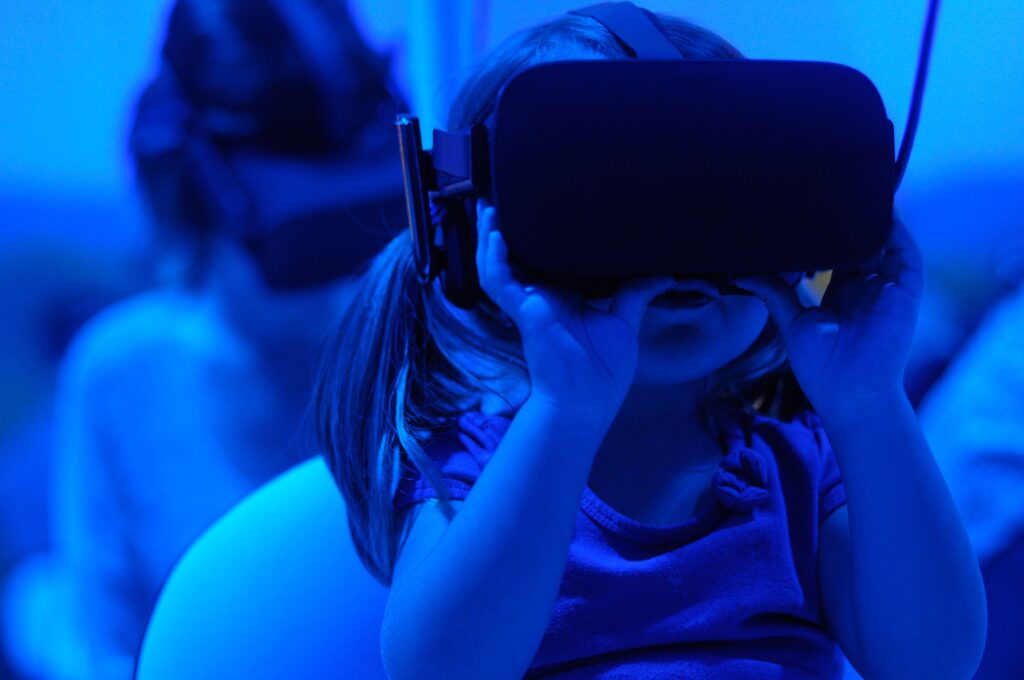 Image of a young girl using a virtual reality goggles as part of an article on online digital learning
